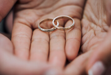 Gold rings in the hands, on the palms of the newlyweds. Wedding photography, macro.