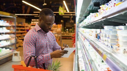Black man makes notes in the shopping list