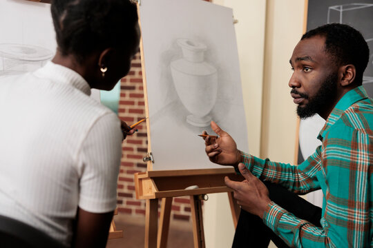 Meeting new friends in art class. Two young African American students man and woman talking communicating during drawing lesson, young black couple learning new things together