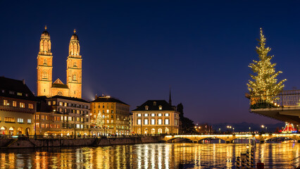 Zurich, Switzerland - November 23, 2023: Anamorphic photo of the old town of Zurich in Christmas time - blue hour. Grossmunster and Limmat river.