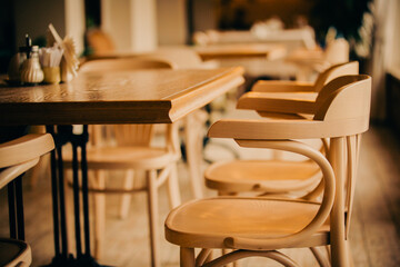 Empty cafe interior in the evening. Wooden tables and elegant wooden chairs. Restaurant fittings. Bar after closing. Rest in a cafe.