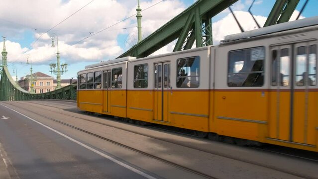 Public tramway route on bridge. A view of yellow and white tramway driving on liberty bridge in the city during day light.