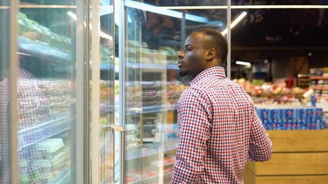 African american man chooses chicken eggs in a farm food store