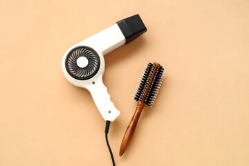 Fototapeta premium Hair dryer and brush on beige background