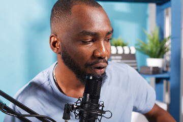 Blogger talking in microphone while recording podcast vlog for internet channel. Young african american man speaking in mic while streaming online in social media networks