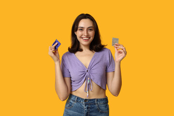 Young woman with condoms on yellow background. Safe sex concept