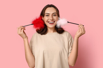 Obraz premium Happy young woman with feather sticks on pink background