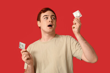 Young man with condoms on red background. Safe sex concept
