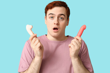 Shocked young man with vibrators on blue background