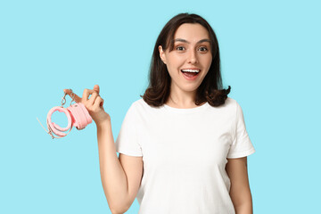 Beautiful young woman with handcuffs on blue background