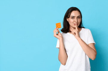 Young woman with condom showing silence gesture on blue background. Safe sex concept