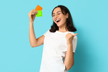Happy young woman with condoms on blue background. Safe sex concept