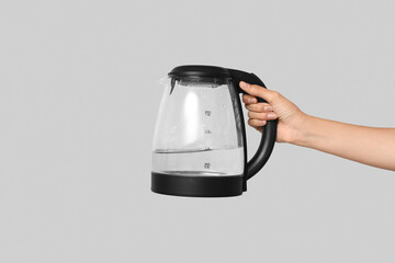 Woman with modern electric kettle on grey background