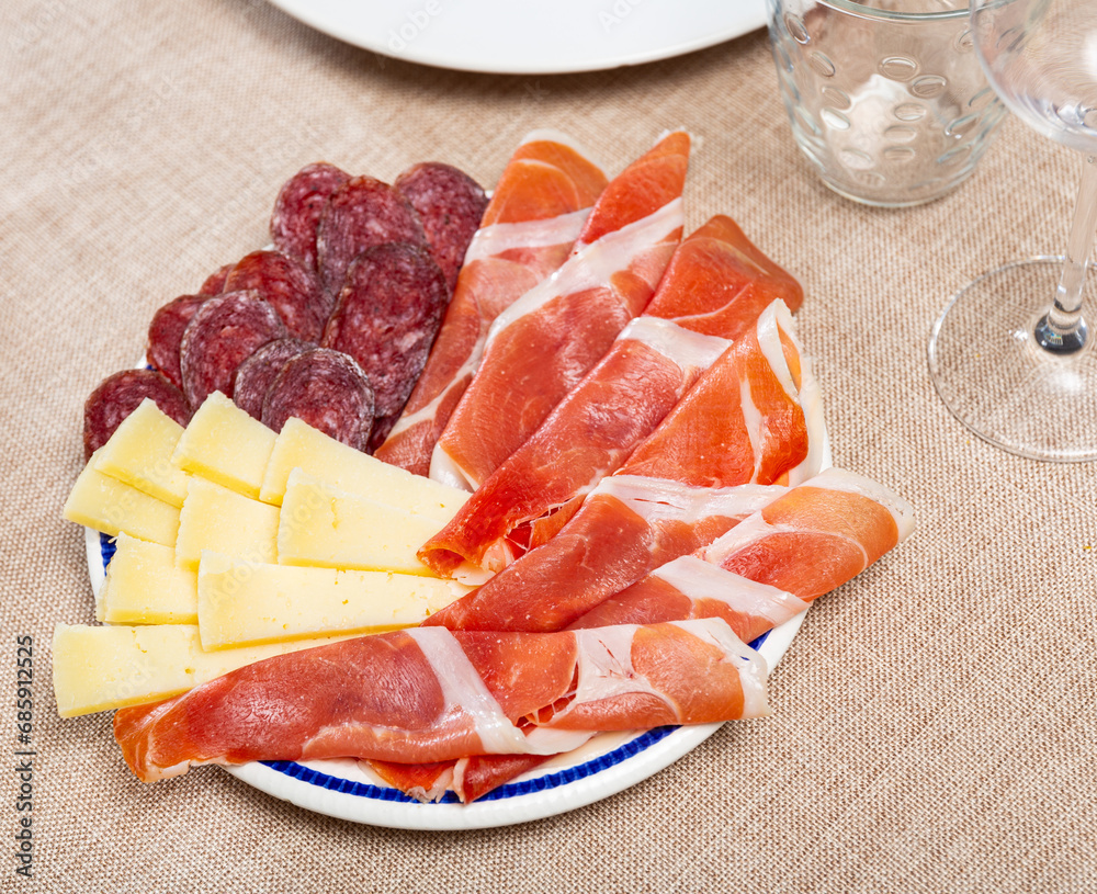 Wall mural service plate containing sliced botifarra, ham and cheese with necessary table laying