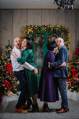 Photo of full family four members christmas gathering senior. A senior couple kisses, the young man grabs his wife's bottom