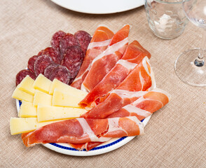 Service plate containing sliced botifarra, ham and cheese with necessary table laying