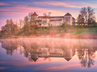 Obraz premium morning fog and colours before sunrise above lake and view to medieval castle