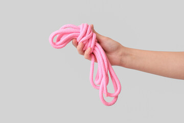 Female hand with pink rope from sex shop on grey background, closeup - obrazy, fototapety, plakaty