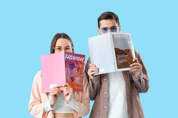 Young couple with magazines on blue background