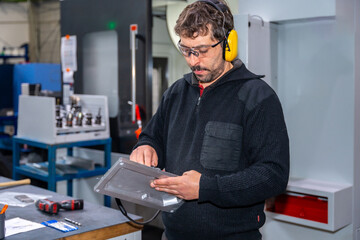 Engineer of a cnc factory using safety headphones working