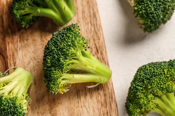 Wooden board with fresh broccoli cabbages on white background, closeup