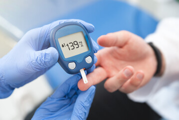 Doctor using glucometer, blood glucose test