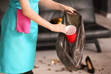 Female janitor bagging trash in office after New Year party, closeup - obrazy, fototapety, plakaty