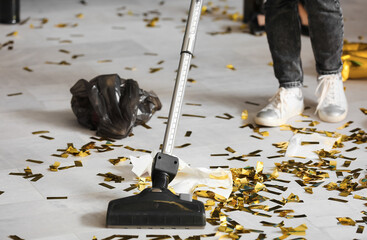 Female janitor cleaning floor in office after New Year party, closeup - obrazy, fototapety, plakaty