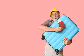 Surprised mature man with passport and suitcase on pink background. Travel concept