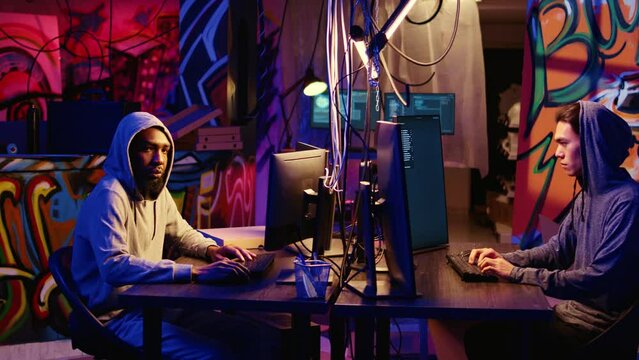 Portrait of security hackers exploring methods of breaching defenses and exploiting weaknesses in computer networks. Malicious programmers in basement getting past firewalls