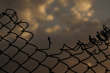 Looking up at a chain link fence with blue sky and clouds. wire fence. Chain link fence see sky....