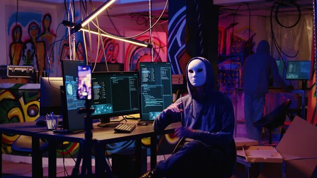 Dissident social justice crusaders doing online activism, wearing anonymous masks and filming video in underground bunker, blackmailing government after stealing secret military documents