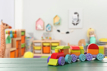 Bright toy train on green wooden table in kindergarten. Space for text