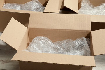 Many open cardboard boxes with bubble wrap on white wooden floor
