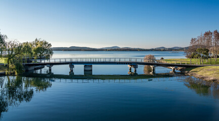 Fototapeta na wymiar A pedestrian bridge in a city park by the lake