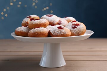 Stand with delicious Hanukkah donuts on wooden table against blurred festive lights