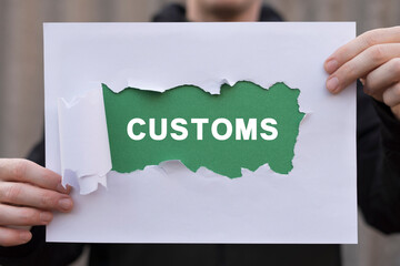 Man holding white and green sheets of paper with word: CUSTOMS. Concept of customs. Customs declaration clearance. Customs registration. Cargo delivery, import and export.