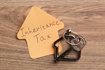 Inheritance Tax. Sticky note and key with key chain in shape of house on wooden table, flat lay