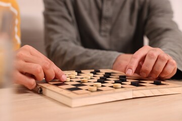Couple playing checkers at wooden table, closeup