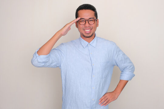 Adult Asian man smiling while giving salute