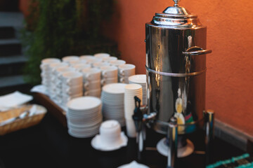 Set of coffee break lunch in the hotel restaurant during conference meeting, with tea and coffee catering, decorated banquet table with white tableware and metal tea maker machine boiler