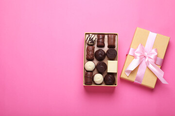 Open box with delicious chocolate candies on pink background, top view. Space for text