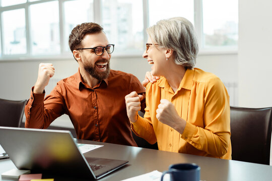 Team overjoyed business people, workers, colleagues using laptop computer win money