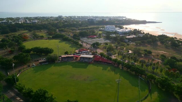 Drone shot of Coastal Sporting Oval with sunset views. AFL Oval Near the beach with red team training for Australian football game