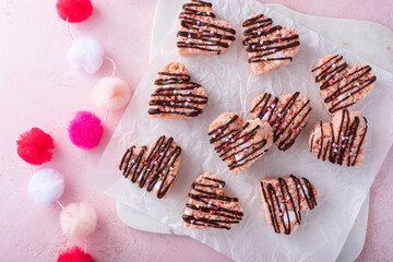 Obraz na płótnie Canvas Pink heart shaped rice krispie treats drizzled with dark chocolate on a marble board