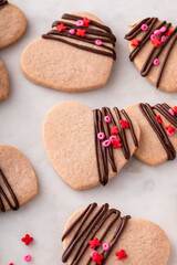 Heart shaped cookies with strawberry flavor, drizzled with dark chocolate with pink sprinkles
