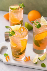 Orange and lime mojito cocktail in tall glasses with lime and mint