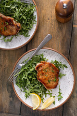Pork chops served with arugula salad on a plate