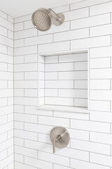 A bathroom shower detail with white subway tile walls, a built-in niche shelf, and a bronze shower...