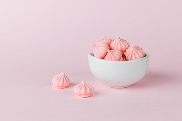 A white bowl with fresh pink meringue on a pink background.